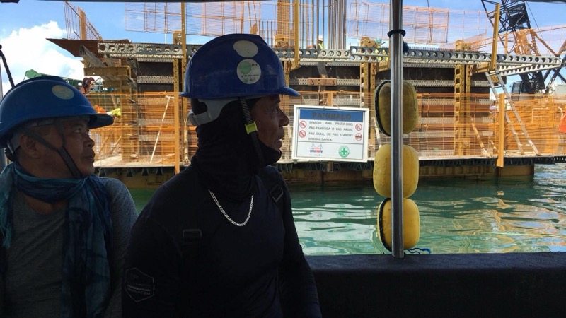 Two divers in wetsuits at pier site with safety signage