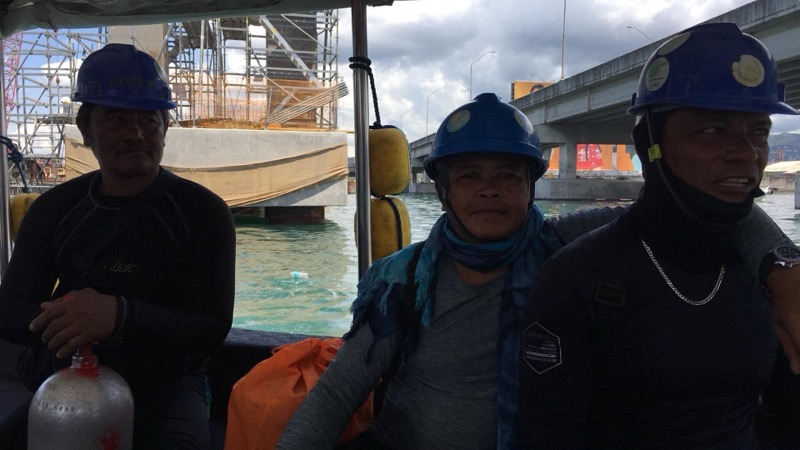 Three divers on boat with blue helmets during bridge construction
